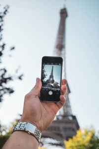 person taking photo of eiffel tower